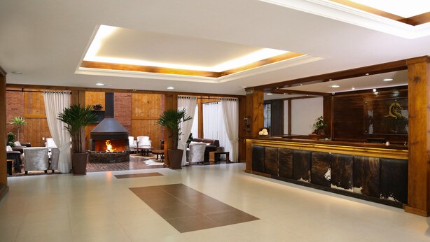 A spacious lobby with a fireplace, seating area, and a reception desk. - Hotel Fazenda Pampas (Canela)