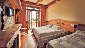 A room with two beds, a wooden bench, a television, and a sliding glass door leading to an outdoor area. - Hotel Fazenda Pampas (Canela)