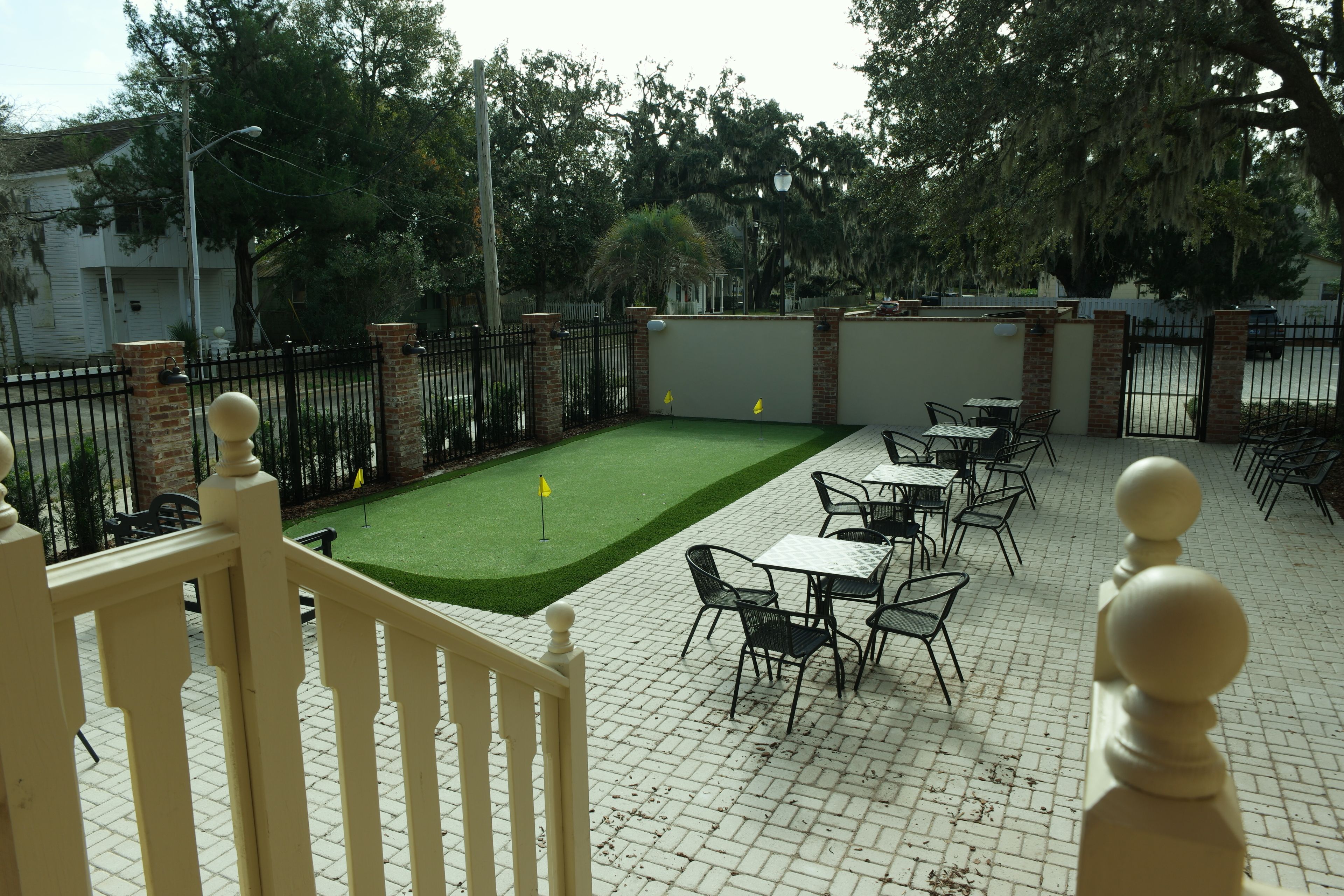 A patio area with a green lawn, tables, chairs, and a brick wall.