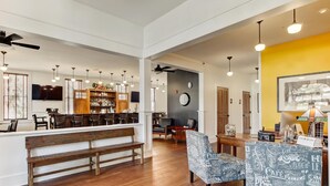 A spacious lobby with a wooden bench, a bar area with shelves, and a dining table with chairs. - Amelia Schoolhouse Inn (Fernandina Beach)