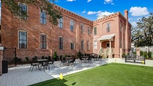 A brick building with a patio area featuring outdoor seating and a well-maintained lawn. - Amelia Schoolhouse Inn (Fernandina Beach)