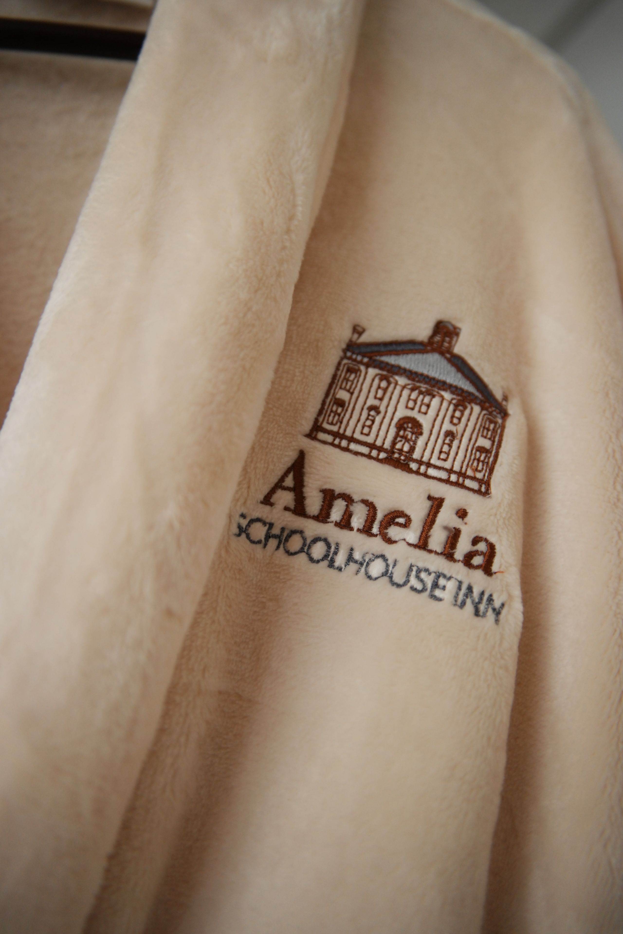 Una manta beige con texto bordado e ilustración de un edificio.
