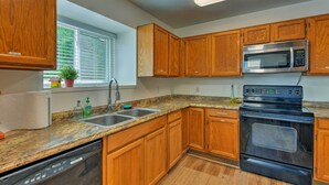Una cucina con mobili in legno, un forno a microonde in acciaio inossidabile, un piano cottura nero e una lavastoviglie.