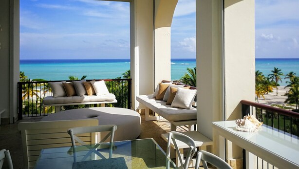 Ein Balkon mit Meerblick, ausgestattet mit einer Couch, Stühlen und einem Tisch.