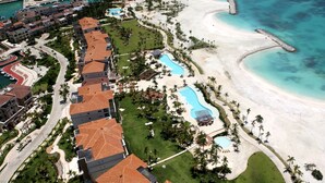 Luftaufnahme eines Resorts mit mehreren Gebäuden, einem Strand und einem Poolbereich.