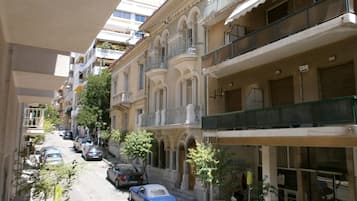 A narrow street lined with multi-story buildings, featuring balconies and a mix of residential and commercial spaces.