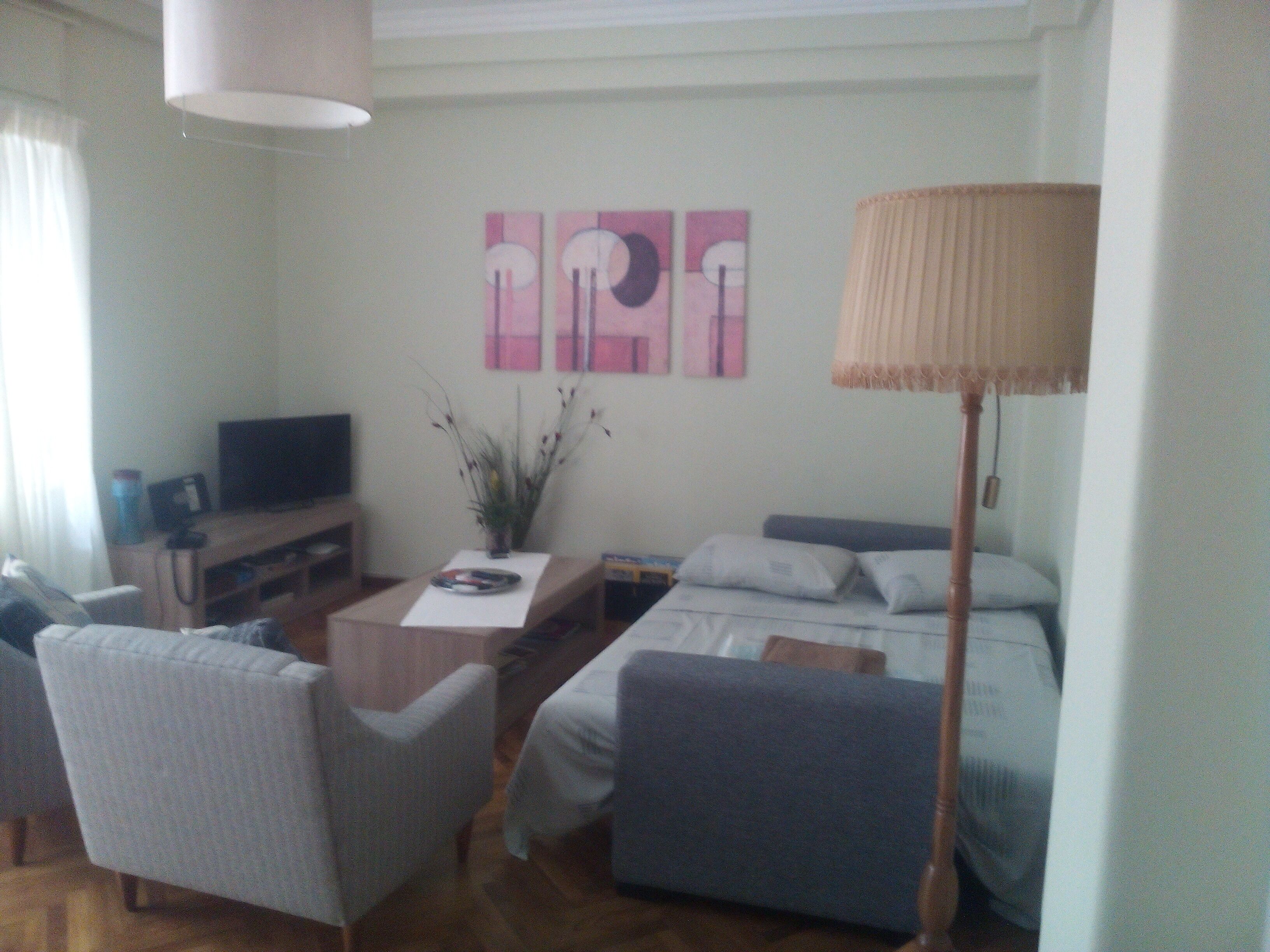 A compact living room with a sofa, a small table, a TV, and a lamp.