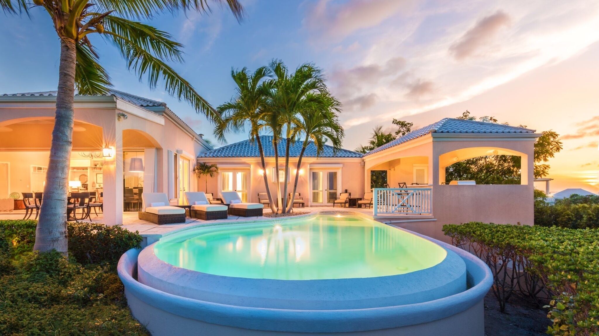 A resort with a swimming pool, lounge chairs, and a covered patio area.