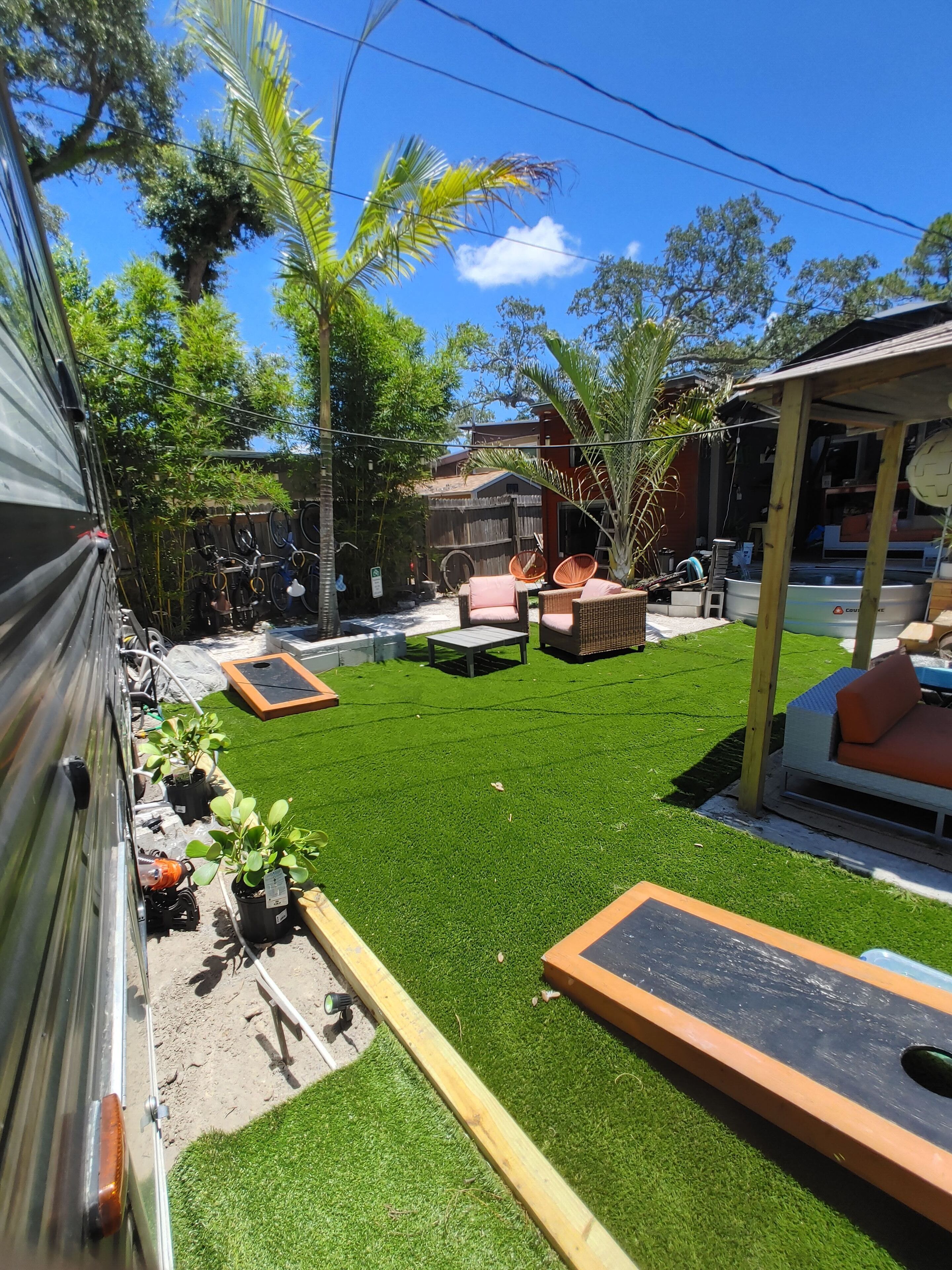 A backyard with artificial grass, outdoor furniture, and a small pool.