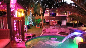 A backyard with a hot tub, a wooden deck, a covered seating area, and a small pool. - With Oasis Shared Backyard (St. Petersburg)