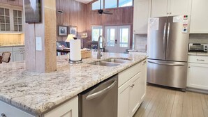 A modern kitchen with a granite countertop, stainless steel appliances, and wooden paneling.
