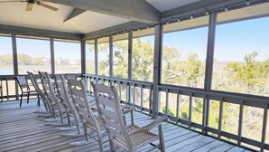 A covered outdoor deck with wooden chairs and a ceiling fan.