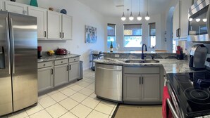 A modern kitchen with stainless steel appliances, a granite countertop, and a central island.