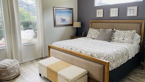 A bedroom with a bed, bedside table, lamp, and a window with curtains.