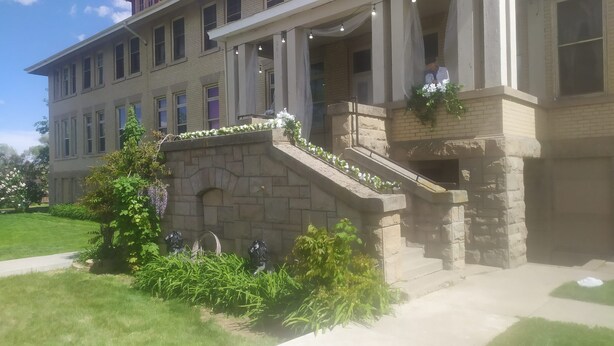 A building with a stone staircase, a balcony with white flowers, and a statue of a lion. - Historic Gooding College, Beautiful Building Small Town up to 21Bedrooms, 13Bath (Gooding)