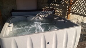 A hot tub with water jets, surrounded by stone walls and a wooden lattice structure. - Historic Gooding College, Beautiful Building Small Town up to 21Bedrooms, 13Bath (Gooding)