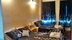 A hotel room with two beds, a nightstand, a lamp, and a window with curtains. - Historic Gooding College, Beautiful Building Small Town up to 21Bedrooms, 13Bath (Gooding)