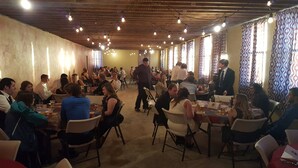 A crowded indoor dining area with tables and chairs, wooden ceiling beams, and patterned curtains. - Historic Gooding College, Beautiful Building Small Town up to 21Bedrooms, 13Bath (Gooding)
