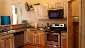 A kitchen with wooden cabinets, a stainless steel dishwasher, a microwave, and an oven. - Historic Gooding College, Beautiful Building Small Town up to 21Bedrooms, 13Bath (Gooding)