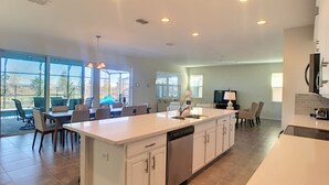Una cocina amplia con una isla central, muebles blancos y lavavajillas.