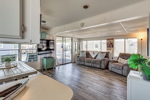 A spacious living room with a large sofa, a dining table, and a television. - Lake Havasu Home w/ Resort Perks, Walk to Lake (Lake Havasu)
