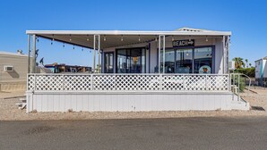 Un caffè sulla spiaggia con una zona coperta per sedersi, un cartello con la scritta 'BEACH' e un cartello accogliente con palme.