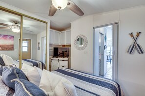 Ein Schlafzimmer mit Bett, Deckenventilator, Fernseher und einem durchgegangenen Tür sichtbar liegenden Badezimmer.