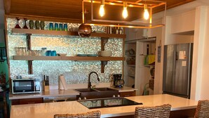 A modern kitchen with a central island, bar stools, a microwave, and a refrigerator. - St Croix vacation rental (Christiansted)