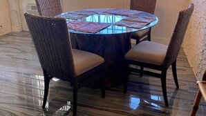 A dining area with a round table, four wicker chairs, and a chandelier with four bulbs. - St Croix vacation rental (Christiansted)
