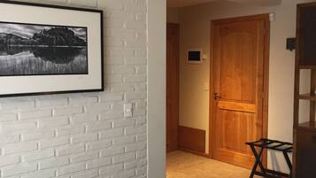 A bedroom with a bed, a framed picture on the wall, a wooden door, and a small table.