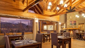 A restaurant with wooden interiors, multiple dining tables, and chairs. - Casona del Alto (San Martín de los Andes)