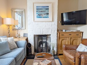 A living room with a fireplace, a sofa, a coffee table, a TV, and a wooden cabinet. - Compass Cottage , Emsworth  -  a cottage that sleeps 4 guests  in 2 bedrooms (Emsworth)