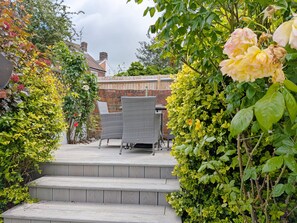 A patio with wicker furniture and steps leading to a garden area. - Compass Cottage , Emsworth  -  a cottage that sleeps 4 guests  in 2 bedrooms (Emsworth)