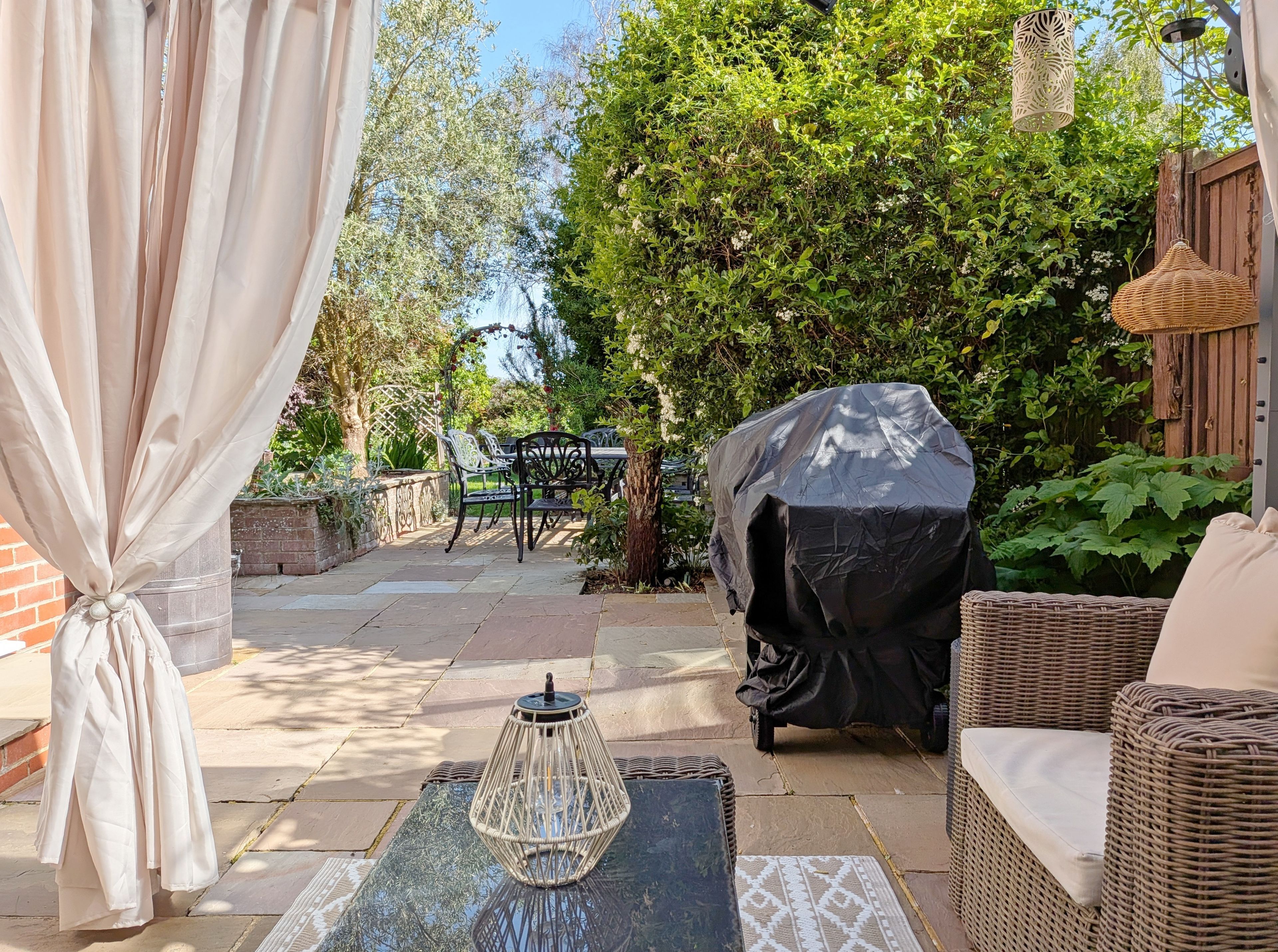 A patio with outdoor furniture, a covered grill, and a decorative lantern.