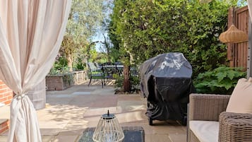 A patio with outdoor furniture, a covered grill, and a decorative lantern.