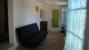 Habitació amb un sofà, un armari de fusta i una porta amb un panell de vidre verd.
