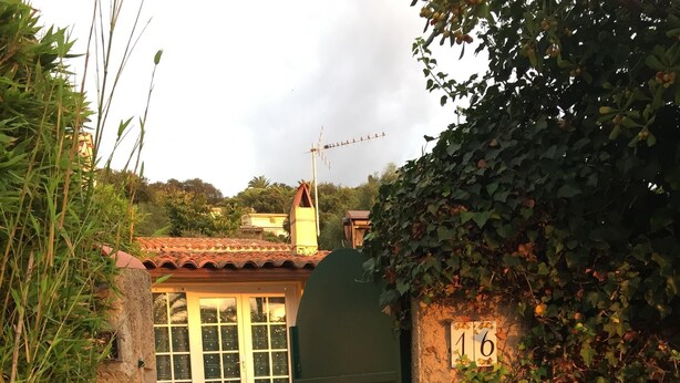 Una entrada tancada amb porta a un edifici amb teulada de rajola, un camí de maons i un senyal amb el número 16.