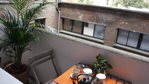 A small balcony with a wooden table, a potted plant, a kettle, cups, and jars. - Apartment TOU T CONFORT, in the HEART of Old Lille, Balconnet (Lille)