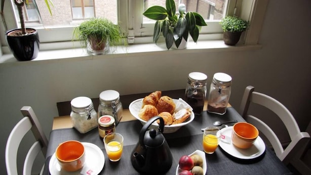 A breakfast table with croissants, fruit, tea, and juice. - Apartment TOU T CONFORT, in the HEART of Old Lille, Balconnet (Lille)