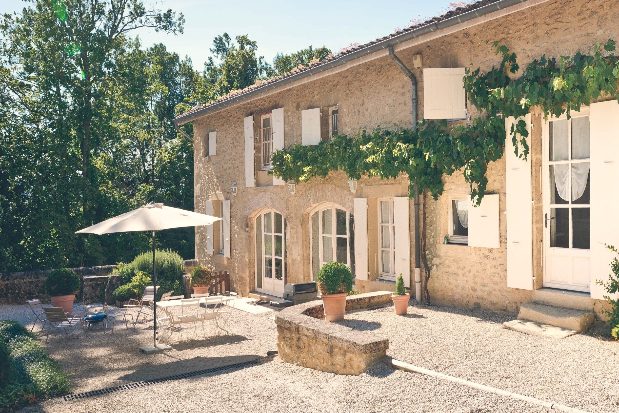 A stone building with a courtyard, outdoor seating, and potted plants.
