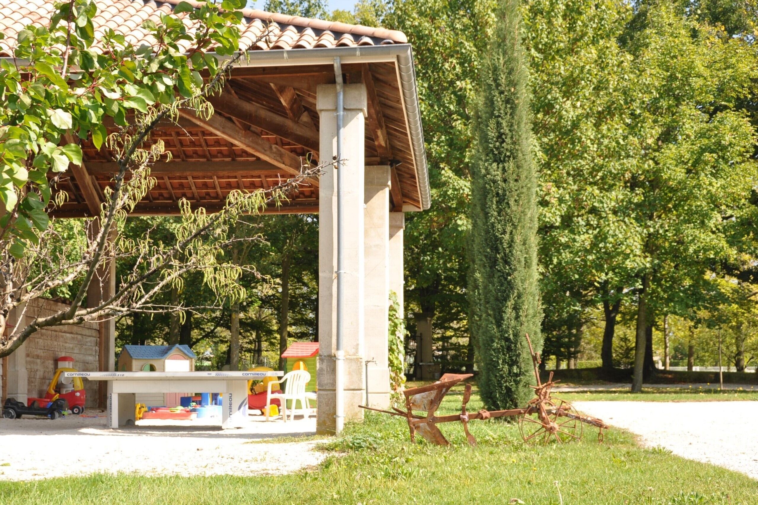 A covered outdoor area with a playhouse, a small table, and a toy truck.