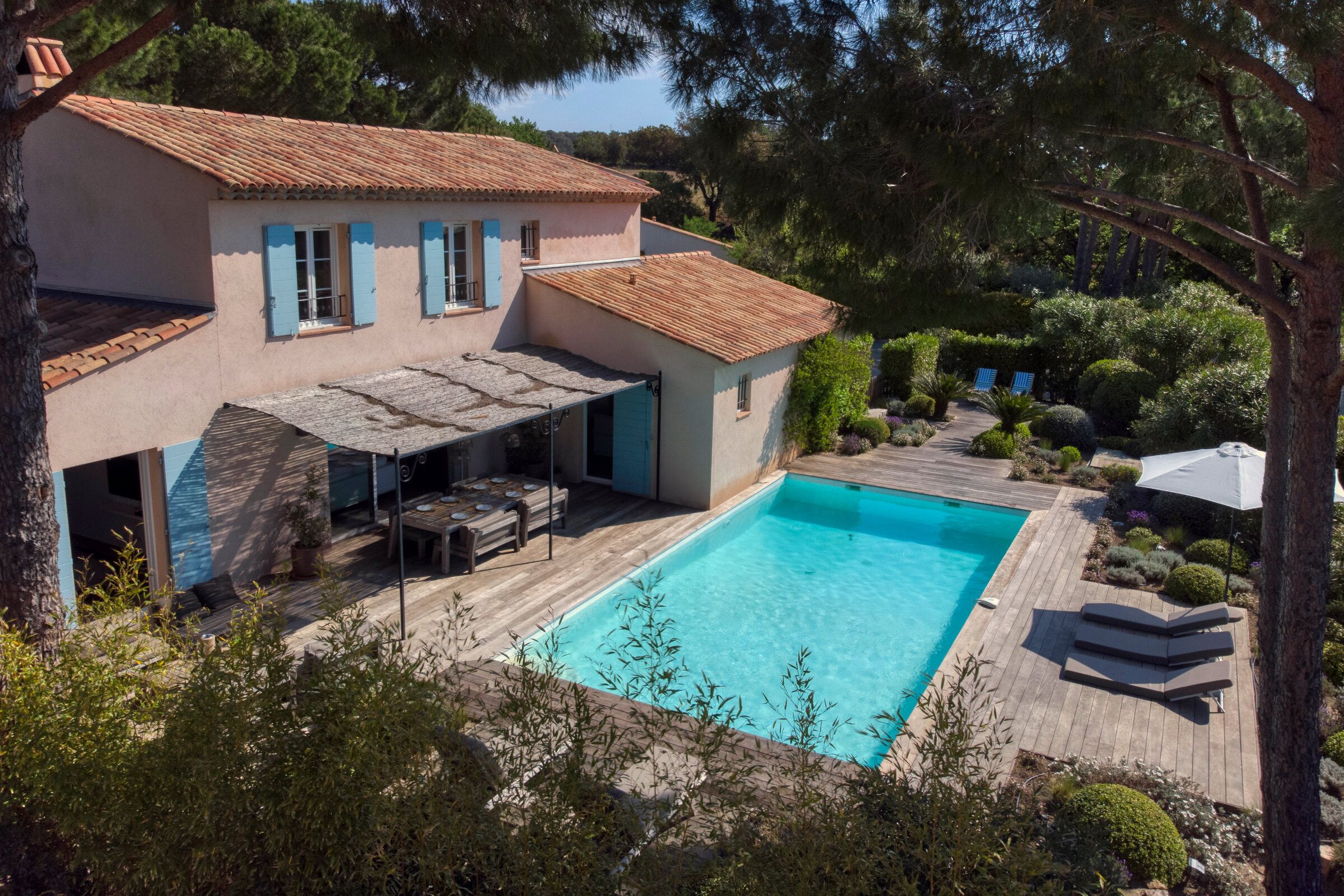 A two-story house with a swimming pool, outdoor seating, and a garden.