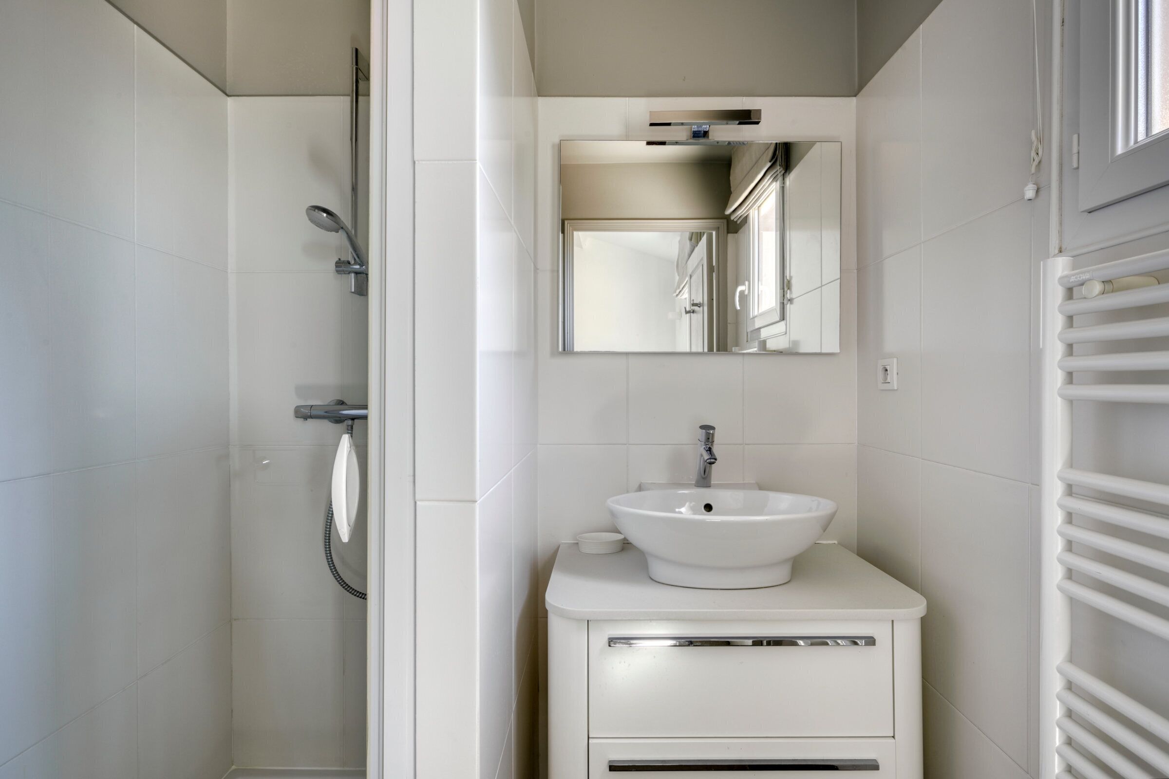 A modern bathroom with a white sink, mirror, and shower.