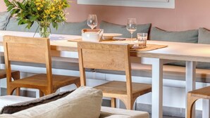 A dining area with a table set for two, a vase of flowers, and a window with a view of greenery. - Luxury villa with private pool - 10 mn from St Tropez (Grimaud)