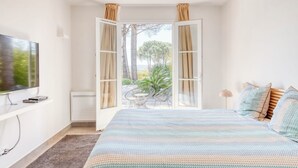 A bedroom with a bed, a TV, a desk, and a window with curtains. - Luxury villa with private pool - 10 mn from St Tropez (Grimaud)