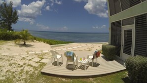 Un patio frente a la playa con mobiliario exterior y vista al océano.