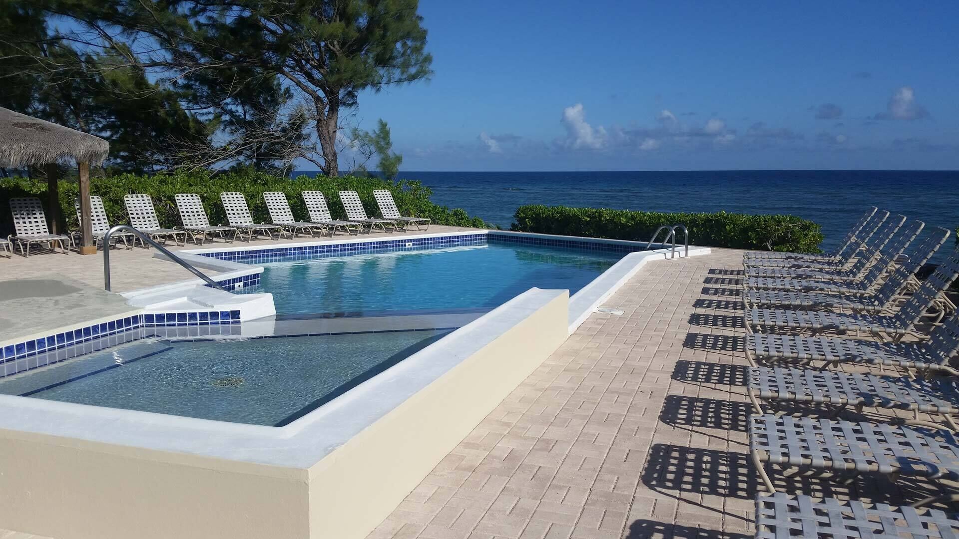 Ein Poolbereich mit Liegestühlen und Blick auf den Ozean.