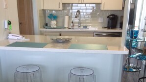 Una cocina con dos taburetes, una encimera y un lavamanos.