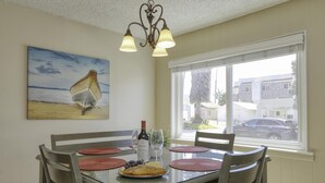 A dining area with a table set for four, a bottle of wine, and a plate of food.