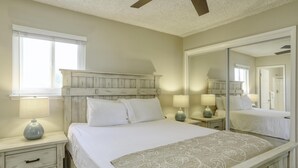 A bedroom with a bed, nightstands, a mirror, and a ceiling fan.